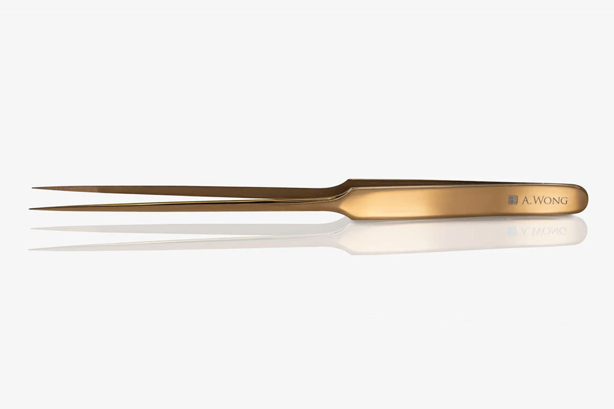 mirrored gold tweezer chopsticks placed on a table