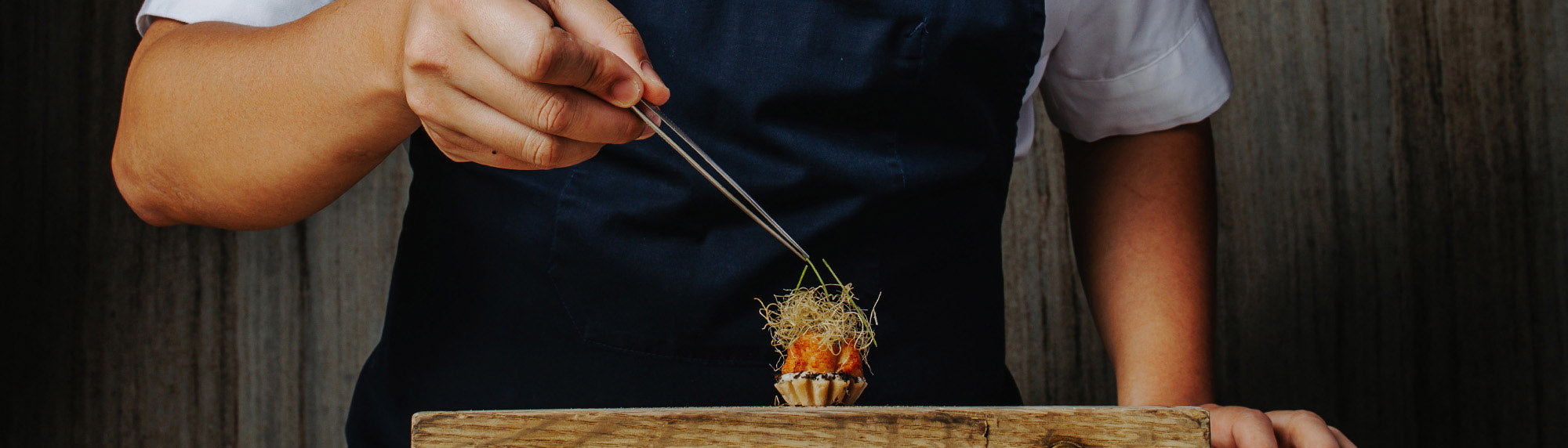 Chef expertly plating some garnish on a dish using Oui Chef angled superfine tweezers